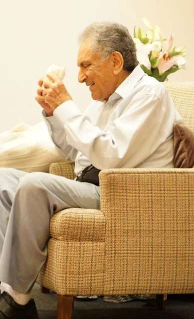 Side view of Ishwar Puri seated with his palms together