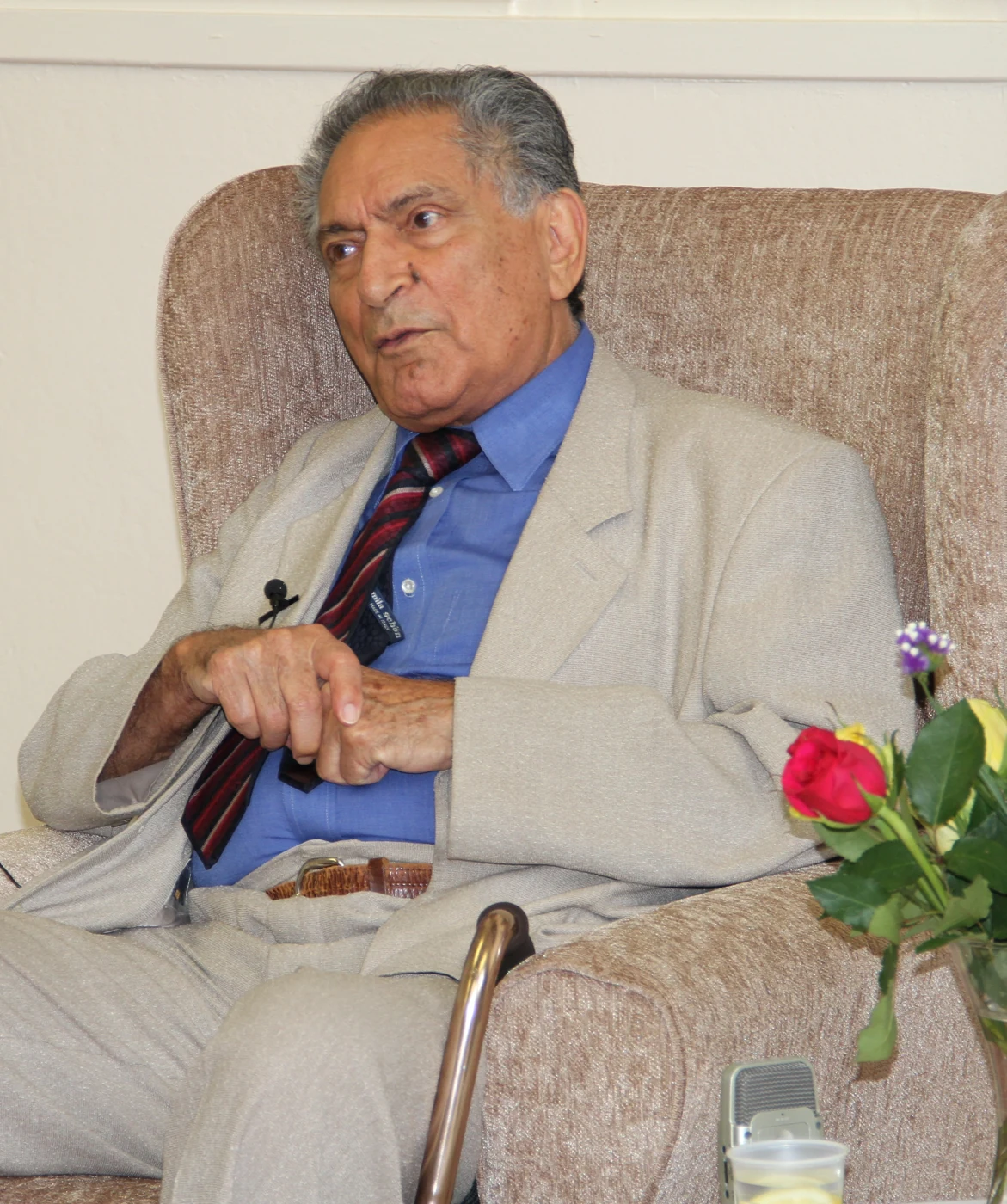 Ishwar Puri seated in an armchair with a microphone